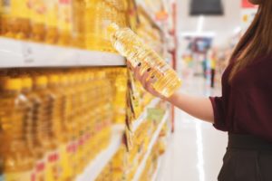 陳列されている商品(油)を女性が手に取っている