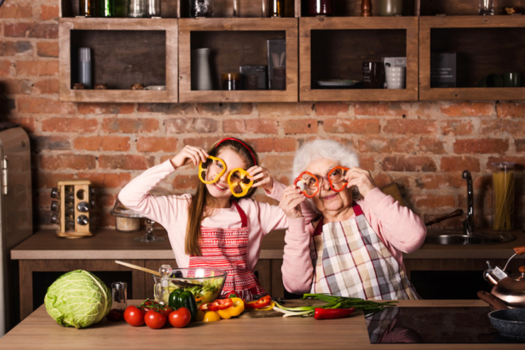 祖母と孫がキッチンで輪切りのパプリカを目に当てて眼鏡の様にしている